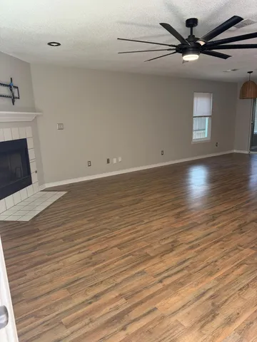 a view of empty room with wooden floor fan and window