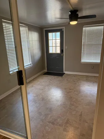 an empty room with wooden floor a ceiling fan and windows