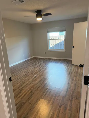 a view of an empty room with wooden floor and closet