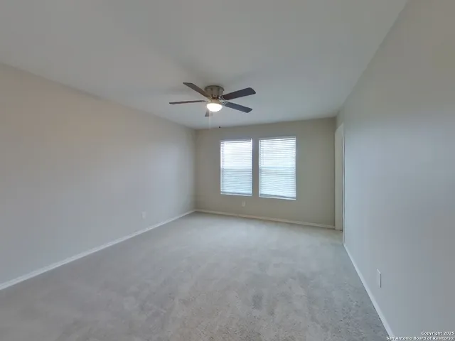 an empty room with windows and ceiling fan