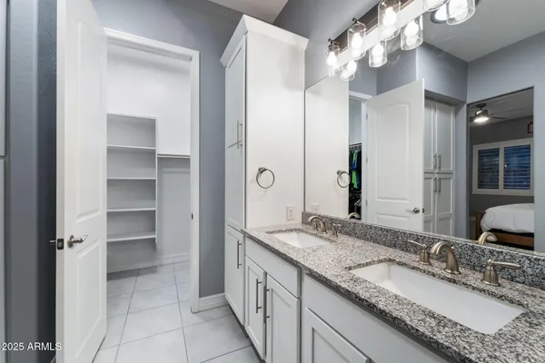 a bathroom with a granite countertop double vanity sink and mirror
