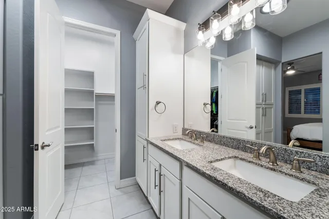 a bathroom with a granite countertop double vanity sink and mirror