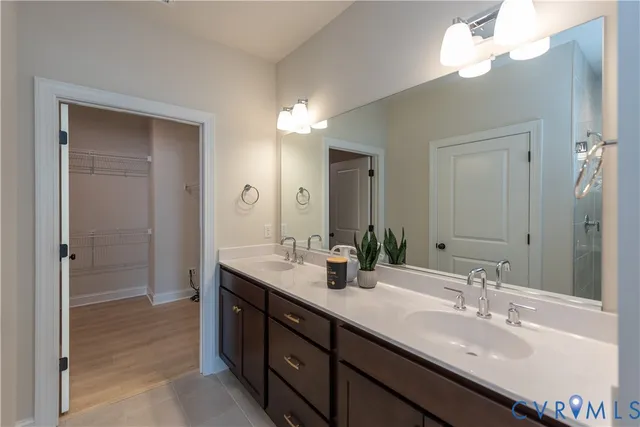a bathroom with double vanity sinks a vanity a lamp and a mirror