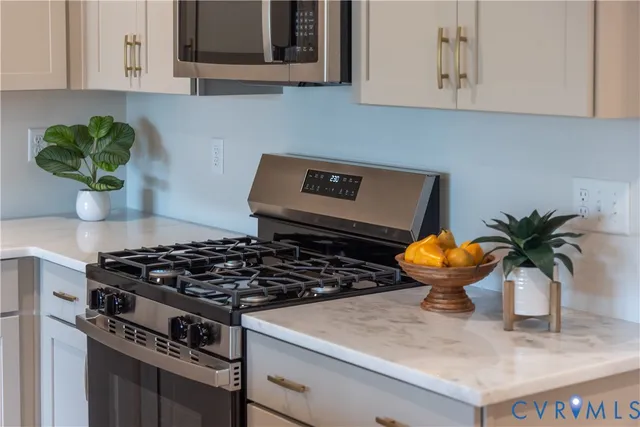a kitchen with stainless steel appliances granite countertop a sink a stove and a white cabinets