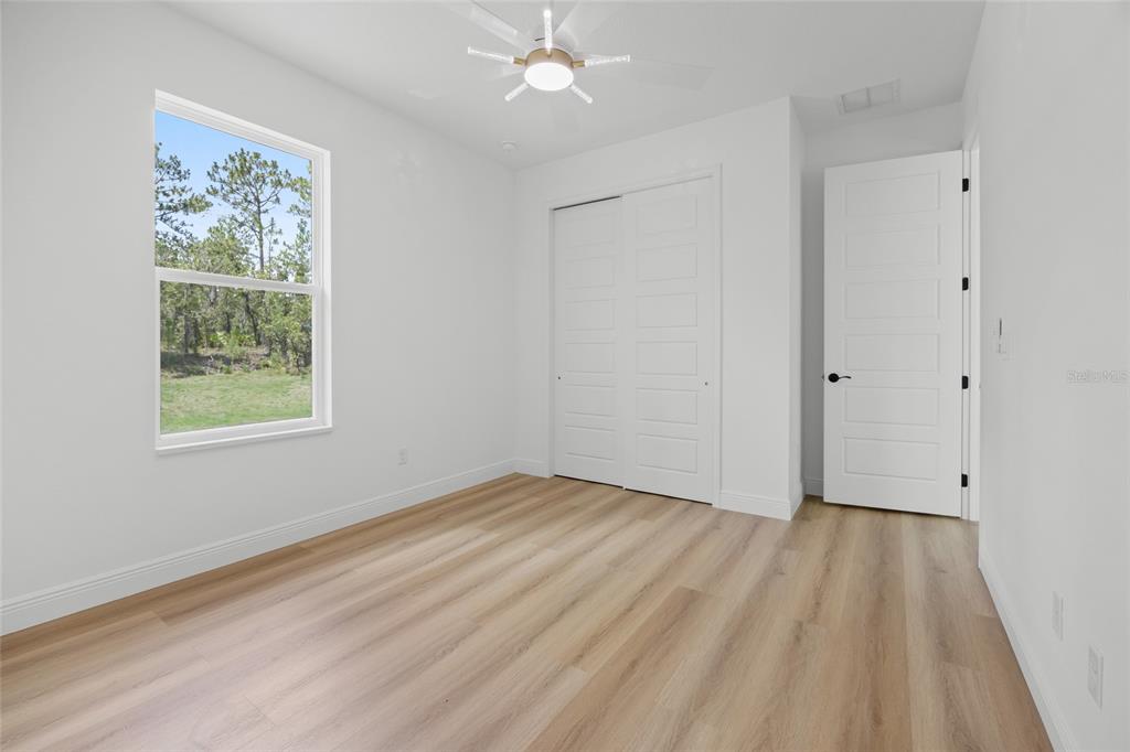 9789 Southwest 125th Ct Road Dunnellon, FL 34432 - Photo 20 of 37 a view of an empty room with wooden floor and a window