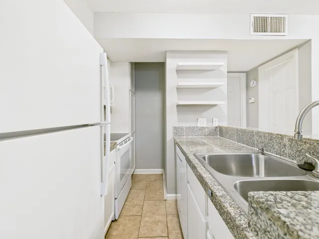 a view of a refrigerator in kitchen and an empty room