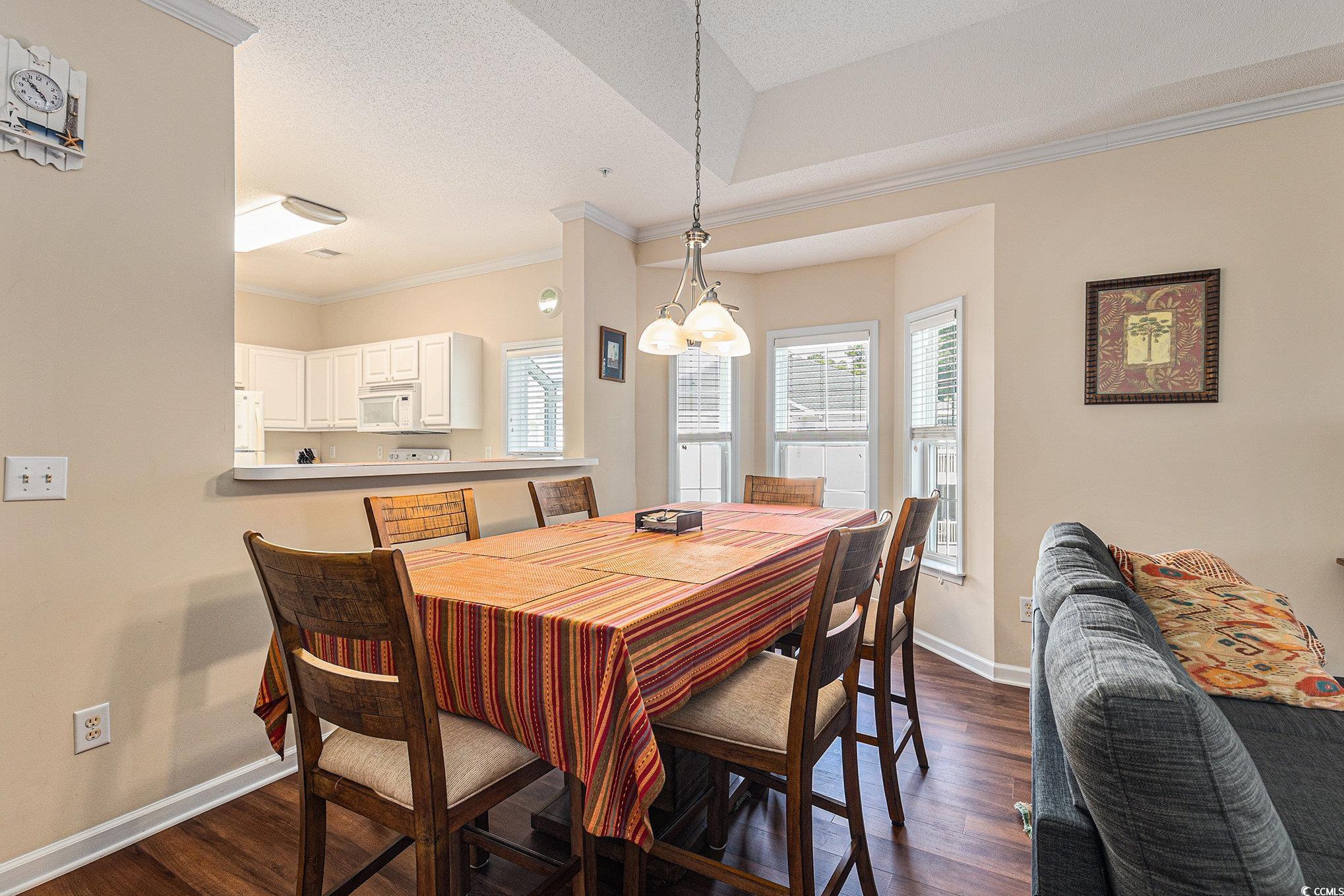 730 Charter Drive, Unit F11 Longs, SC 29568 - Photo 10 of 32 Dining space featuring dark wood-type flooring, crown molding, a raised ceiling, ceiling fan, and a chandelier