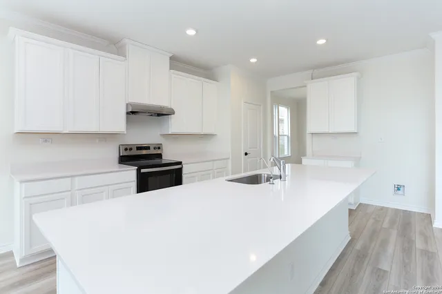 a kitchen with stainless steel appliances a sink a stove and white cabinets