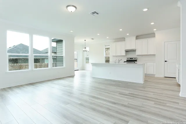 a view of a kitchen with kitchen island a sink wooden floor and a large window