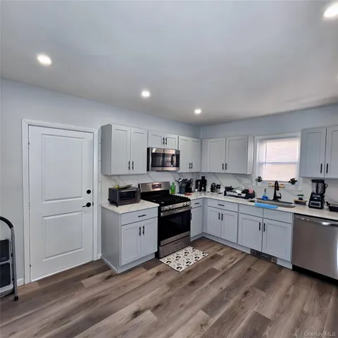 a kitchen with granite countertop a sink cabinets and stainless steel appliances