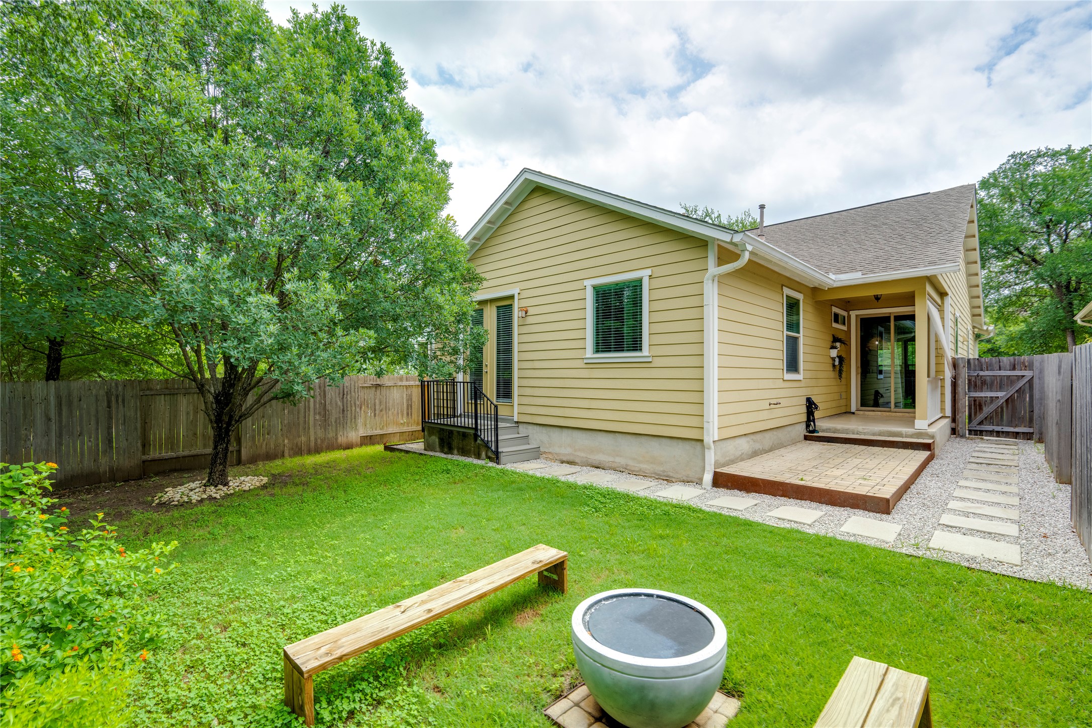6008 Whipple Way Austin, TX 78745 - Photo 36 of 39 A well-maintained backyard with a large tree, wooden fence, and a patio area, perfect for outdoor enjoyment.