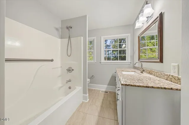 a bathroom with a granite countertop sink and a bathtub