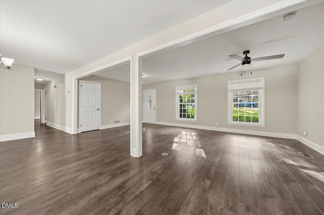an empty room with wooden floor chandelier and windows