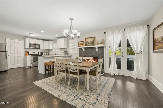 a dining room with wooden floor a chandelier a wooden table and chairs