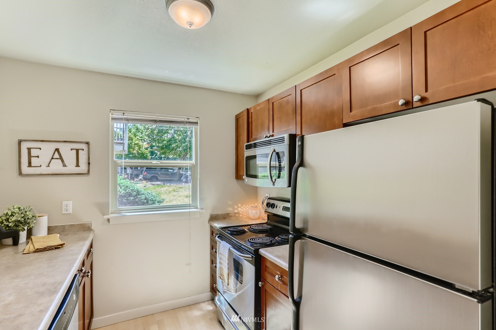 9805 Avondale Road Northeast, Unit X162 Redmond, WA 98052 - Photo 4 of 19 a kitchen with stainless steel appliances granite countertop a stove a sink and a refrigerator with wooden cabinets