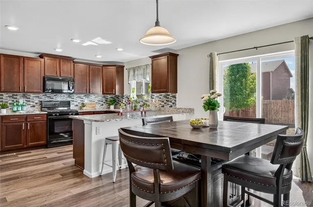 a kitchen with stainless steel appliances granite countertop a kitchen island hardwood floor sink stove dining table and chairs
