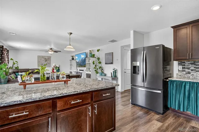 a kitchen with granite countertop a refrigerator a stove and wooden cabinets