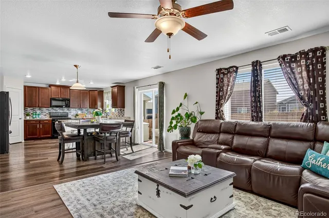 a living room with furniture kitchen view and a wooden floor