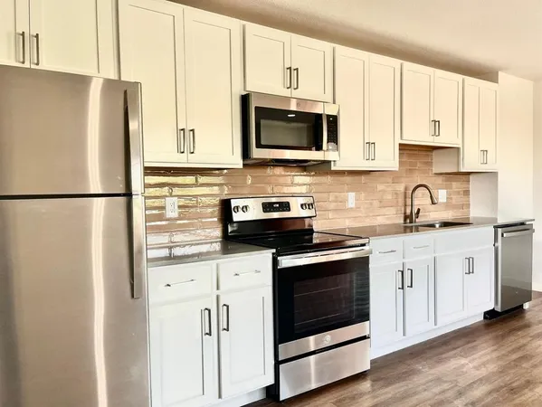 a kitchen with stainless steel appliances white cabinets and a refrigerator