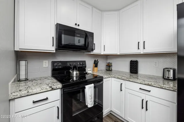 a kitchen with granite countertop white cabinets and a stove a oven with white countertops