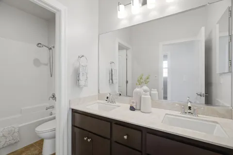 a bathroom with a double vanity sink toilet mirror and bathtub