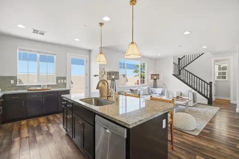 a kitchen with stainless steel appliances granite countertop a sink a stove and a wooden floor