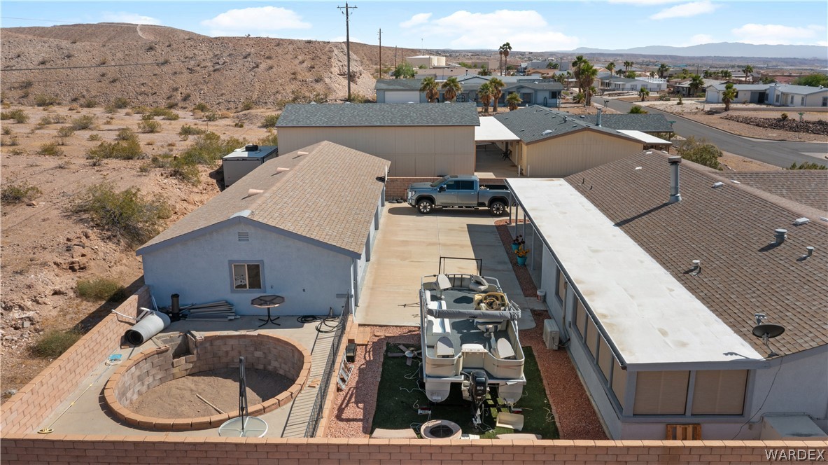 784 Pegasus Ranch Road Bullhead City, AZ 86429 - Photo 99 of 100 Expansive property featuring a concrete driveway, a large carport, a block-walled backyard, an in-ground circular fire pit, and a single-story structure with a covered patio