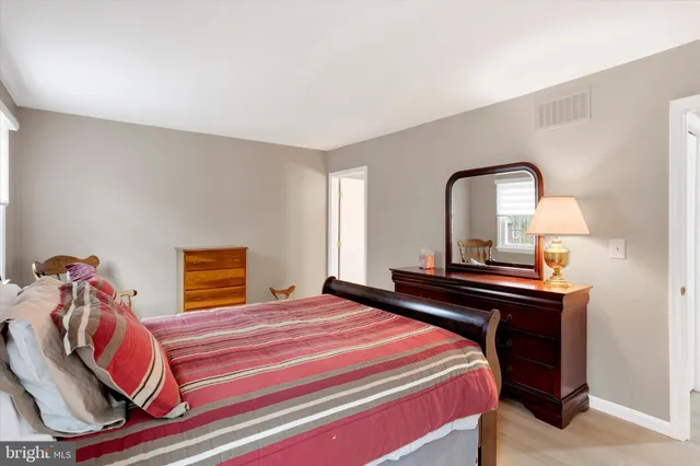 a bedroom with a bed and a potted plant on the dresser