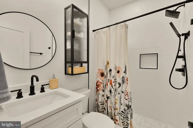 a bathroom with a sink vanity mirror and toilet