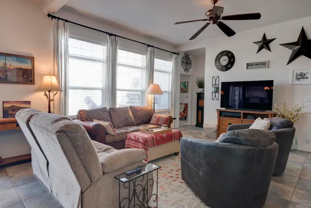 a living room with furniture a ceiling fan and a large window
