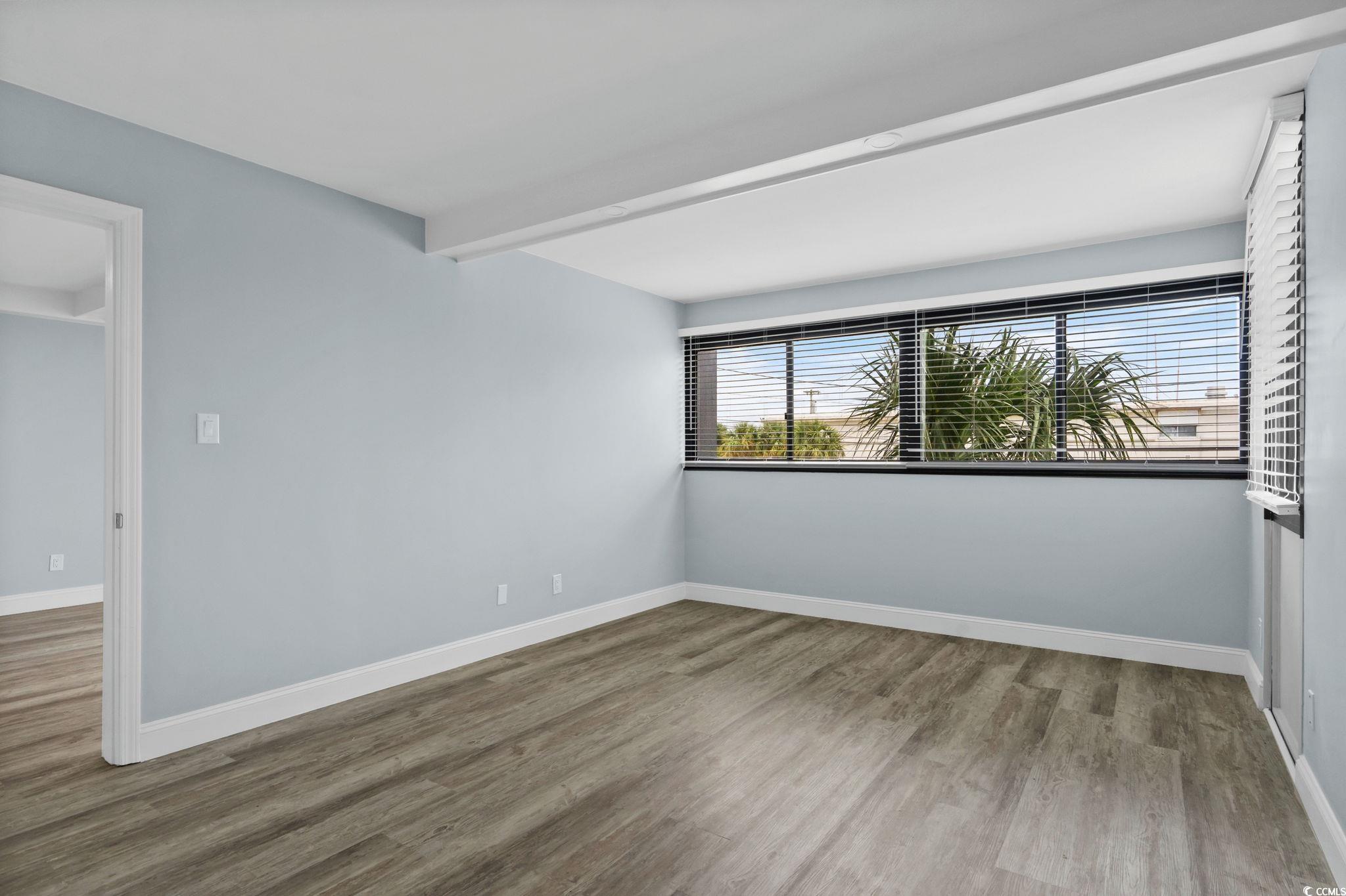 601 Mitchell Drive, Unit 207 Myrtle Beach, SC 29577 - Photo 15 of 38 Empty room with wood finished floors, plenty of natural light, and beamed ceiling