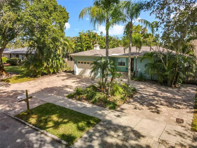 a backyard of a house with table and chairs under an umbrella
