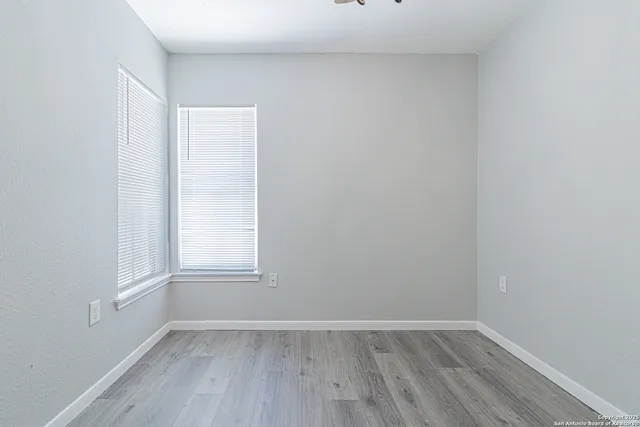 a view of an empty room with wooden floor and window