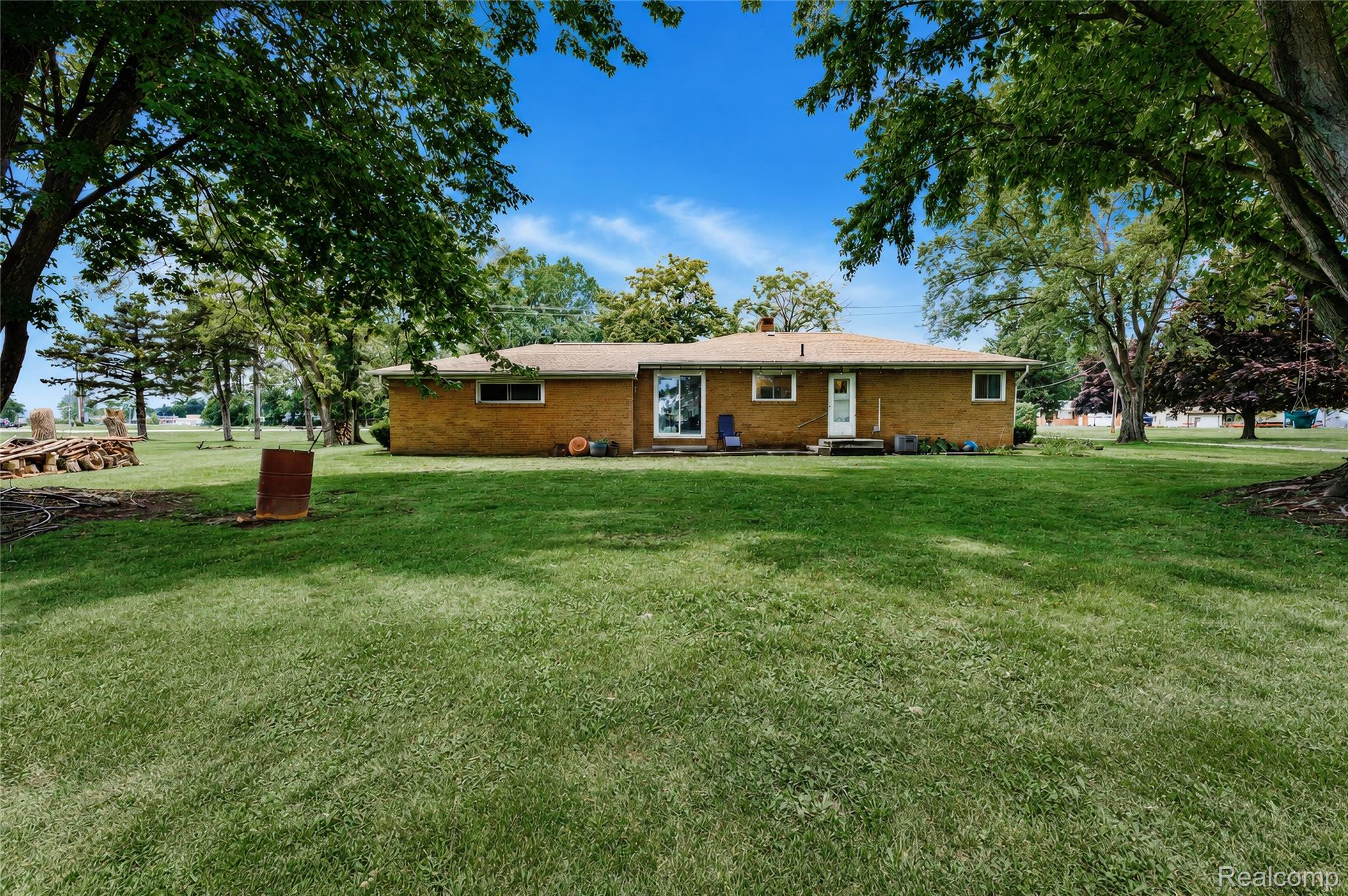 4499 South Linden Road Flint, MI 48507 - Photo 32 of 36 Expansive green lawn with mature trees, brick exterior, and multiple windows