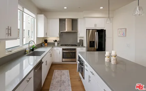 a large kitchen with stainless steel appliances a sink a stove and a refrigerator