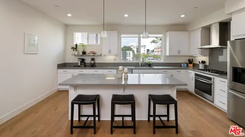 a kitchen with kitchen island granite countertop a table chairs sink and stove top oven