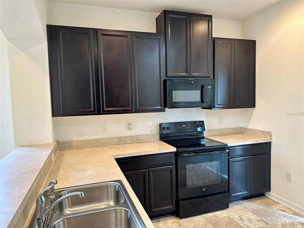 7006 Spotted Deer Place Riverview, FL 33578 - Photo 4 of 21 a kitchen with stainless steel appliances granite countertop a stove and a refrigerator with wooden cabinets