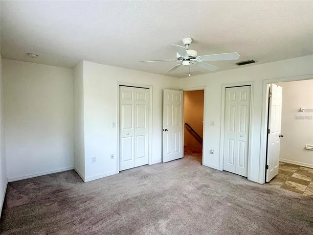 an empty room with closet and a ceiling fan