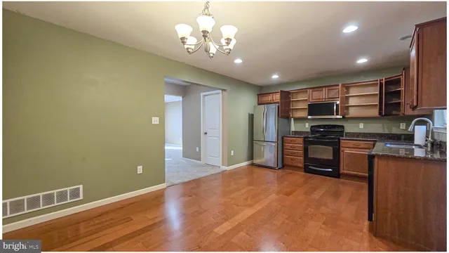 a open kitchen with stainless steel appliances granite countertop a refrigerator and a stove top oven