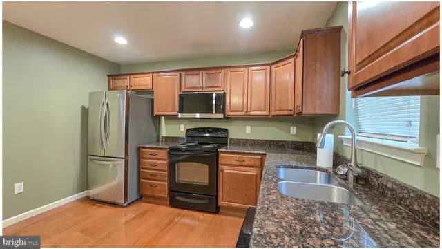 a kitchen with granite countertop a refrigerator and a stove top oven