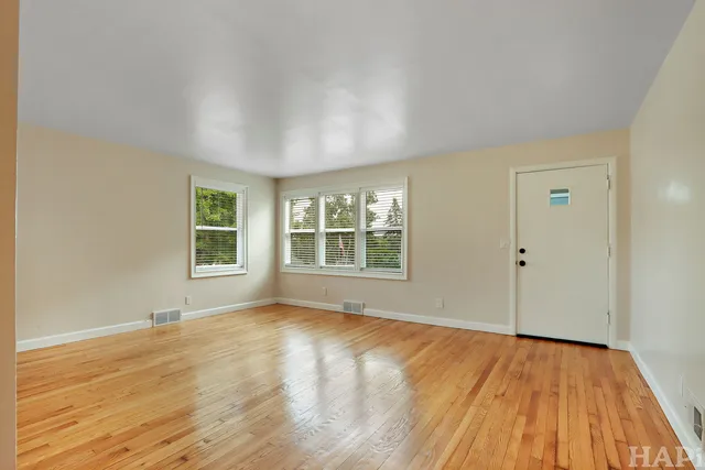 a view of an empty room with wooden floor and a window