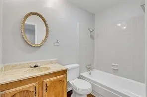 a bathroom with a granite countertop toilet a sink and a mirror