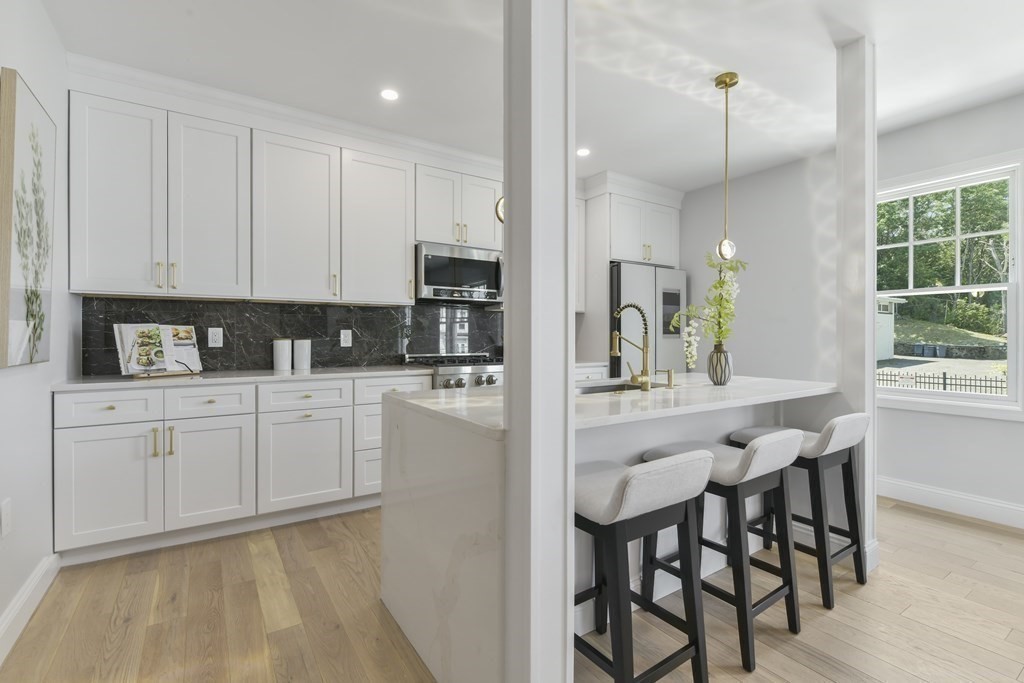 137 Falcon Street, Unit 4 Boston, MA 02128 - Photo 5 of 22 a kitchen with stainless steel appliances kitchen island granite countertop a table chairs sink and cabinets