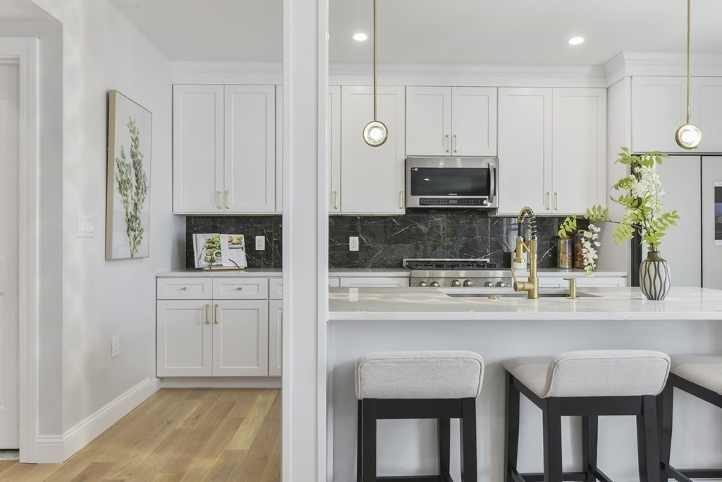 137 Falcon Street, Unit 4 Boston, MA 02128 - Photo 7 of 22 a kitchen with stainless steel appliances kitchen island granite countertop a stove a sink and a microwave