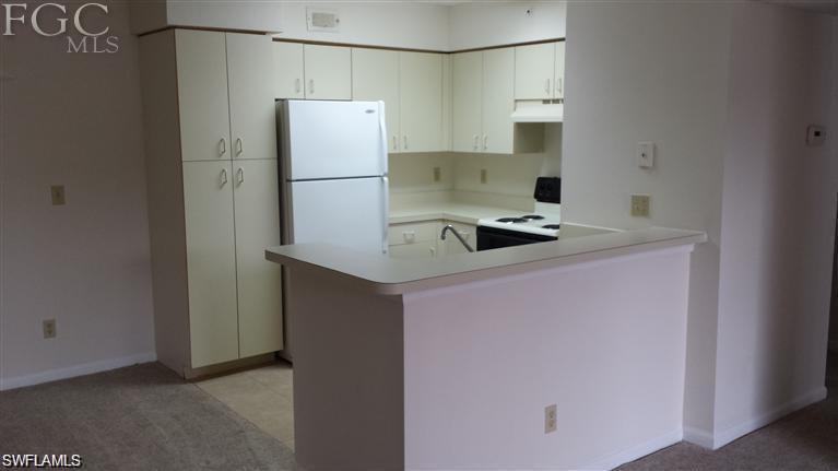 13521 Eagle Ridge Drive, Unit 128 Fort Myers, FL 33912 - Photo 13 of 14 a kitchen with stainless steel appliances granite countertop a sink and a refrigerator