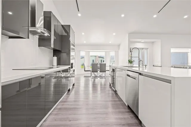 a large white kitchen with lots of counter space wooden floor and stainless steel appliances