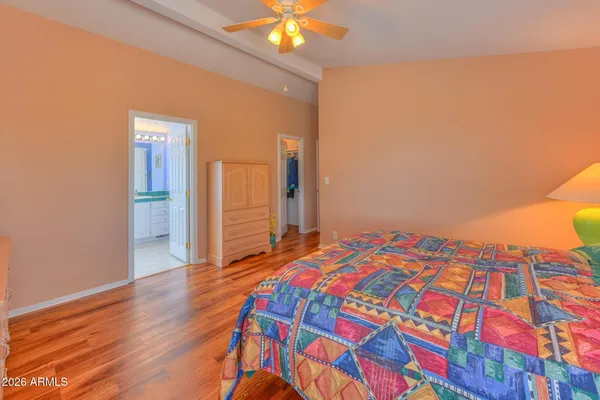 a bedroom with a bed and a dresser with wooden floor