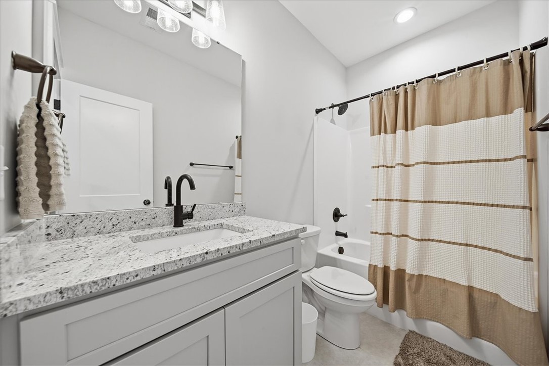 214 Timothy Court Anderson, SC 29621 - Photo 22 of 43 A well-lit primary bathroom features granite counters and a clean, functional tub with a shower.
