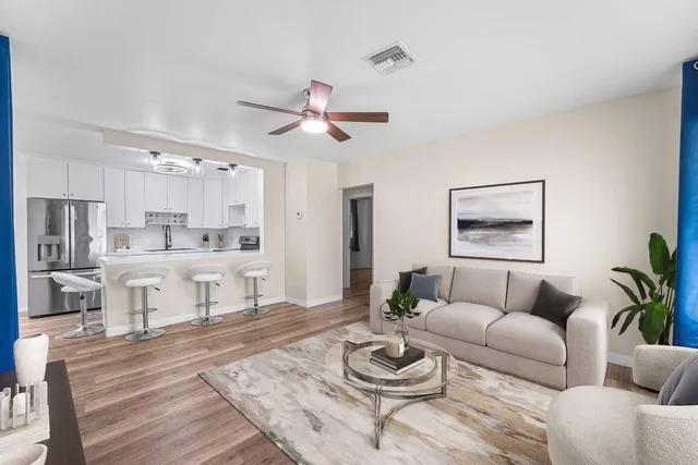 a living room with furniture kitchen view and a potted plant