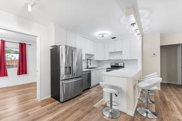 a kitchen with a refrigerator cabinets and wooden floor